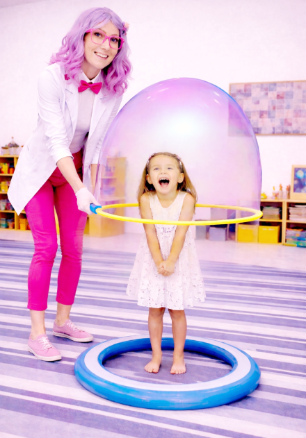 Child standing inside a giant bubble during a safe, indoor bubble science incursion with floor protection